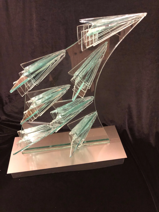 Abstract sculpture composed of bonded glass shards mounted on a stainless steel base, featuring layered geometric forms in translucent greenish-blue hues.
