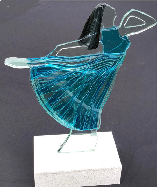 Bonded glass sculpture of a ballett dancing woman in a flowing blue dress, mounted on a white stone base.