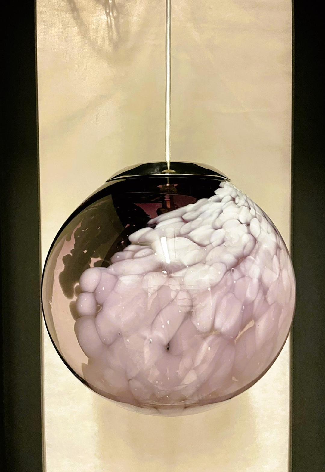 Single artisan pendant light featuring a delicate, semi-translucent lavender and white marbled glass globe, suspended against a neutral cream and black background.