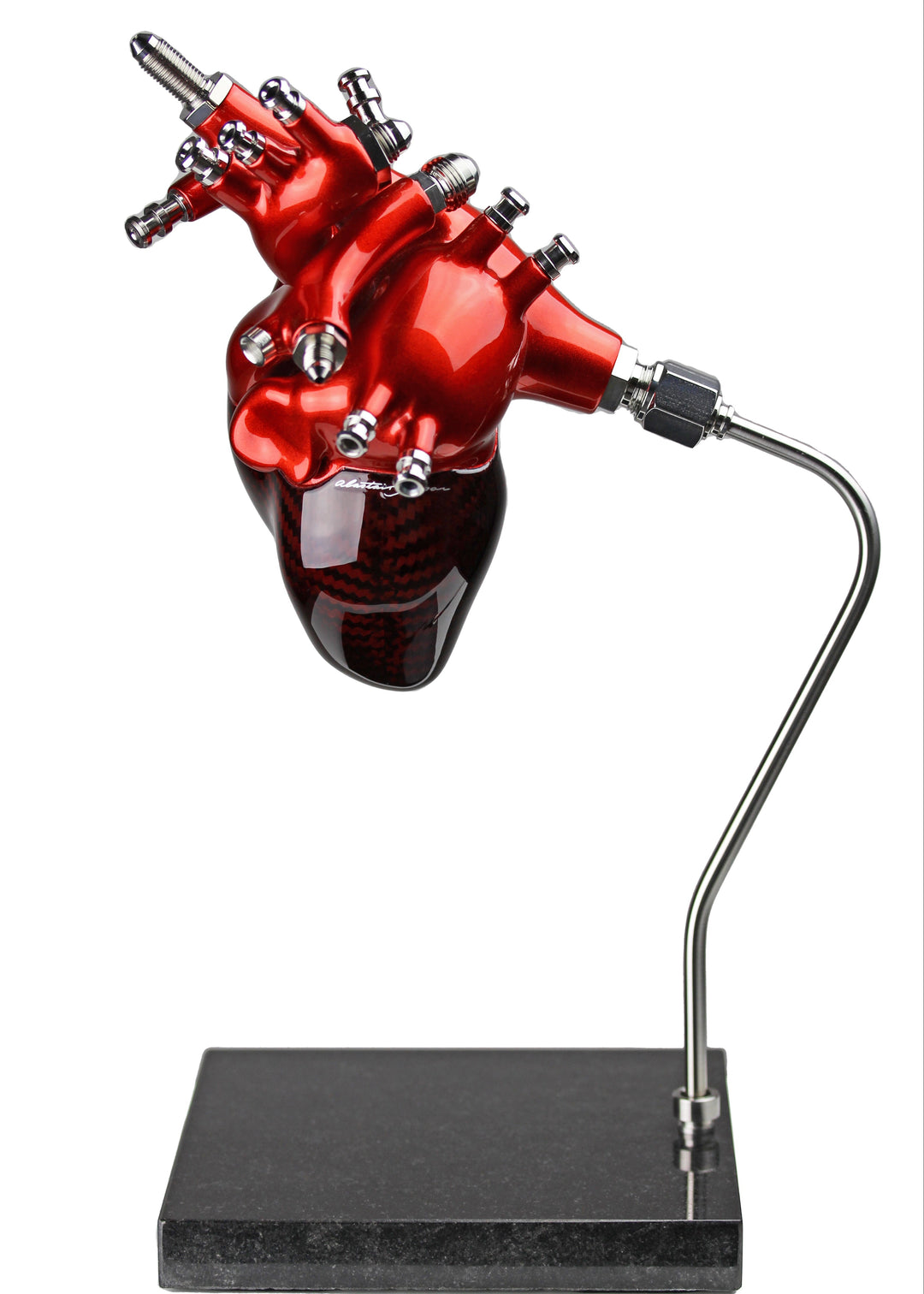 A vivid heart sculpture by Alastair Gibson, crafted from red-tinted 2x2 twill carbon fibre and finished with 3D-printed ABS atriums. Featuring titanium fuel and hydraulic fittings from Grand Prix cars, it fuses organic form with motorsport engineering. Finished in deep racing red with a UV-resistant gloss, it’s desk-mounted on a polished granite base with a stainless steel hydraulic support—blending precision with striking visual impact.