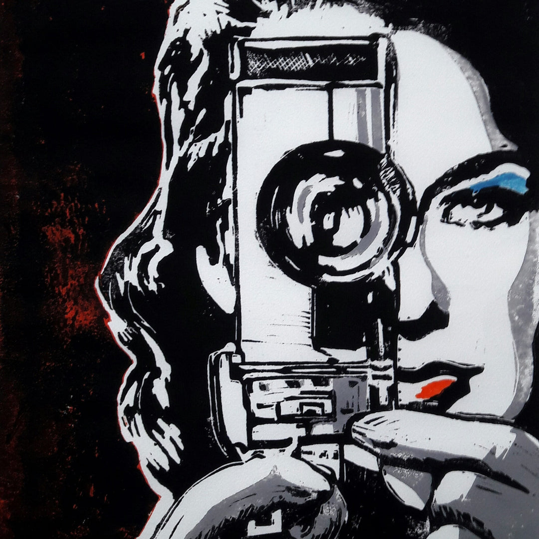 Striking black-and-white linocut of a woman holding a vintage cine camera up to her eye, her gaze locked through the lens. Accents of bold blue eyeshadow and bright red lipstick punctuate the monochrome palette, adding pop-art contrast to the intense stare. The composition evokes voyeurism, glamour, and retro cinema with textured edges and hand-rendered detail.
