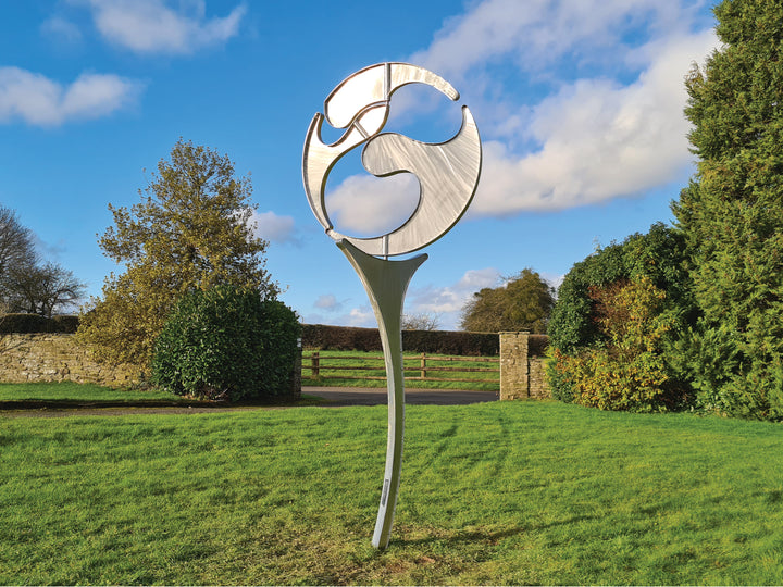 Abstract stainless steel kinetic sculpture with rotating, wind-driven elements and curved forms designed for outdoor movement