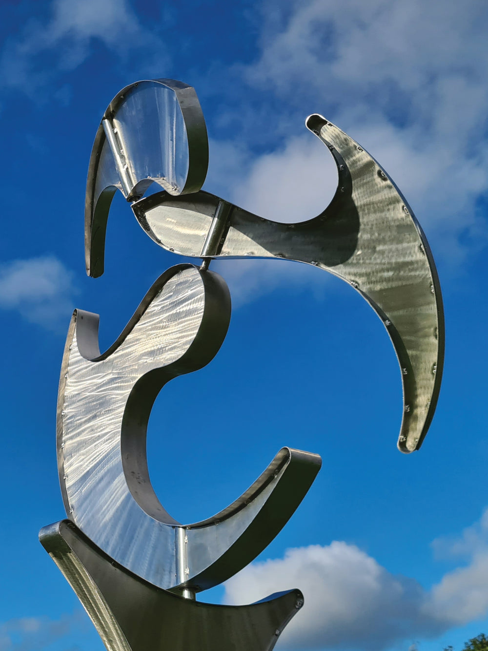 Abstract stainless steel kinetic sculpture with rotating, wind-driven elements and curved forms designed for outdoor movement