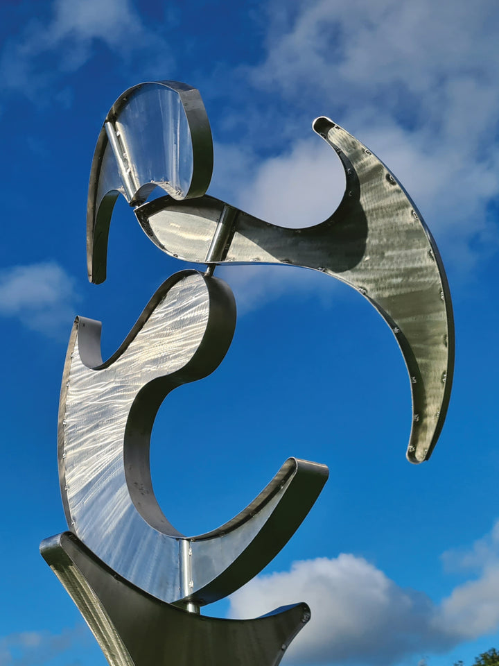 Abstract stainless steel kinetic sculpture with rotating, wind-driven elements and curved forms designed for outdoor movement