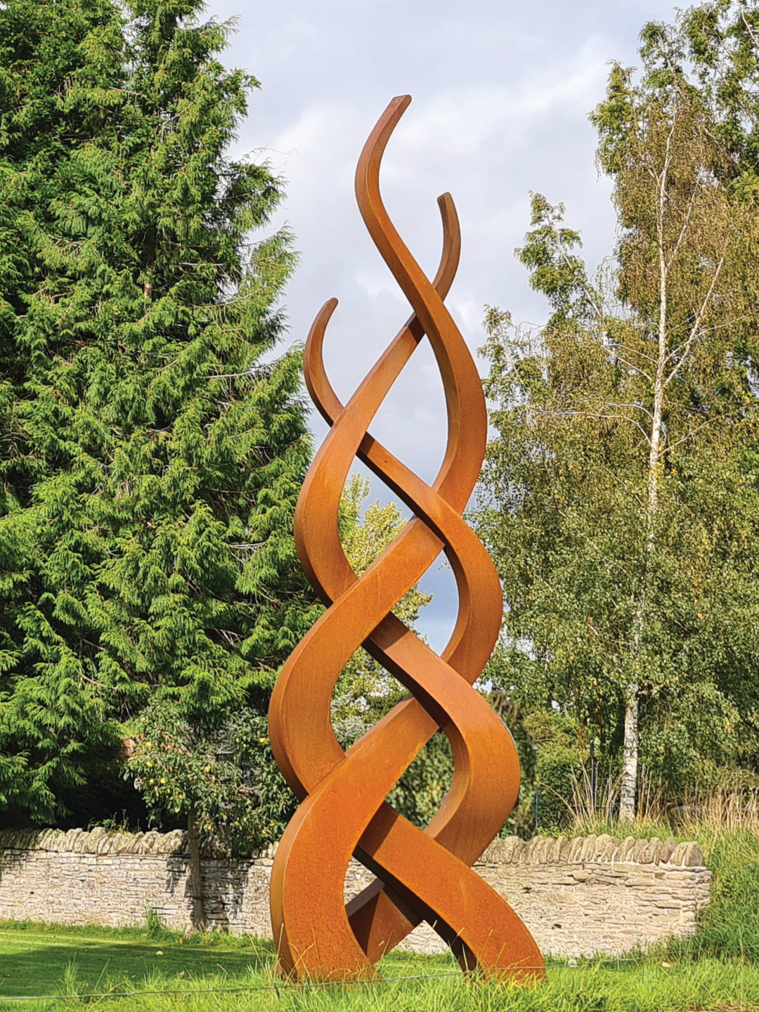 Tall corten steel sculpture featuring three intertwined flame-like forms in a rusted finish, rising gracefully from the ground