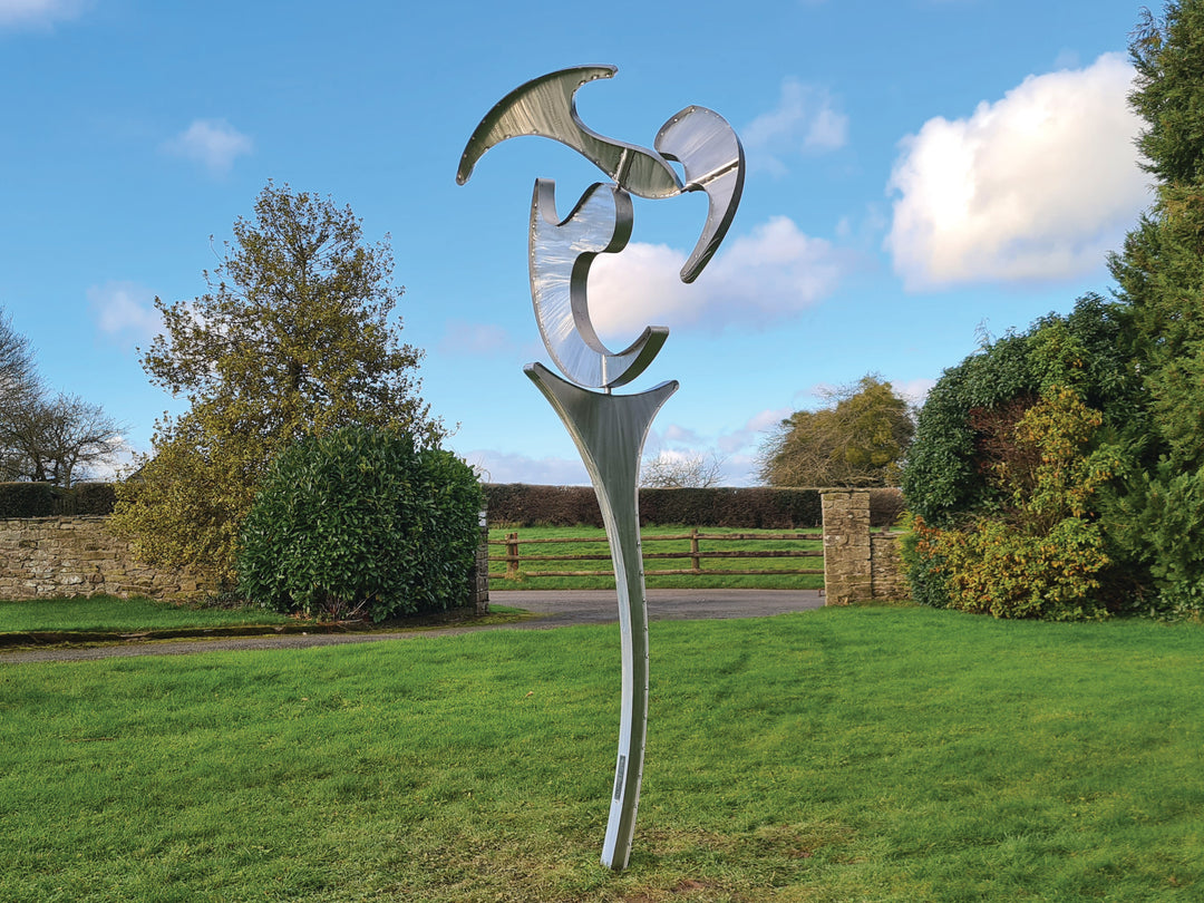 Abstract stainless steel kinetic sculpture with rotating, wind-driven elements and curved forms designed for outdoor movement