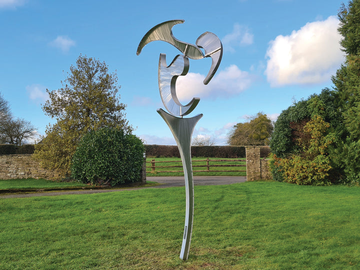 Abstract stainless steel kinetic sculpture with rotating, wind-driven elements and curved forms designed for outdoor movement
