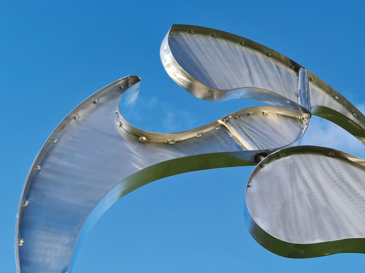 Abstract stainless steel kinetic sculpture with rotating, wind-driven elements and curved forms designed for outdoor movement
