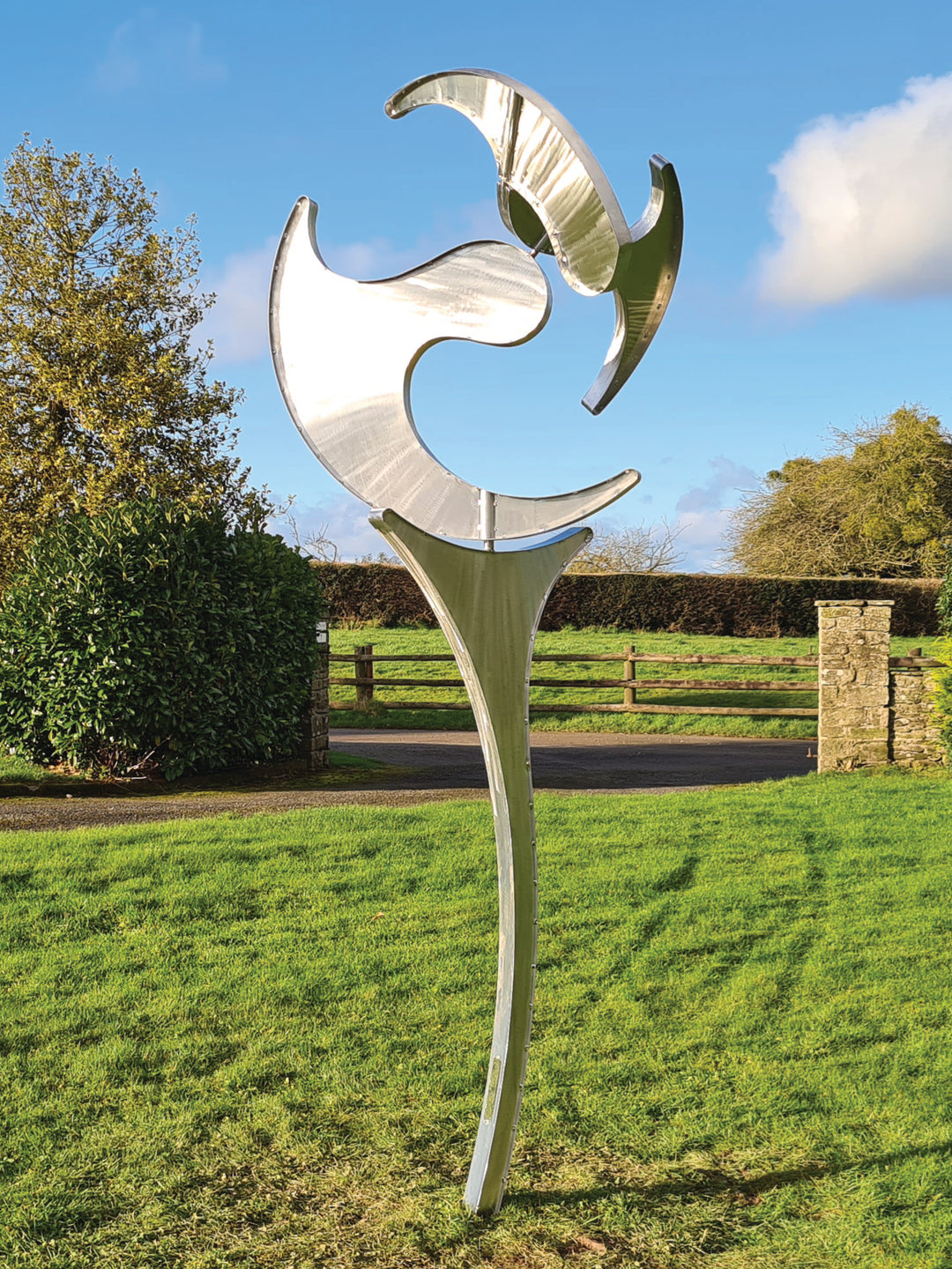 Abstract stainless steel kinetic sculpture with rotating, wind-driven elements and curved forms designed for outdoor movement