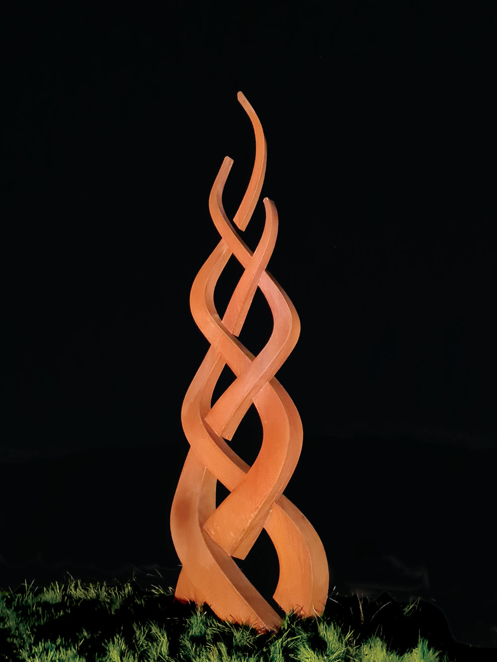 Tall corten steel sculpture featuring three intertwined flame-like forms in a rusted finish, rising gracefully from the ground