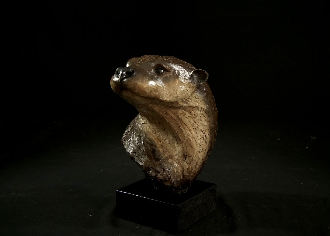 Cold cast stone sculpture of an otter head and neck titled Hindsight by Jamie Lord — finely detailed bust with sleek, sinuous form, warm brown fur tones, dark glassy eyes and alert, turned-back pose. Limited edition of 24 with signed Certificate of Authenticity.