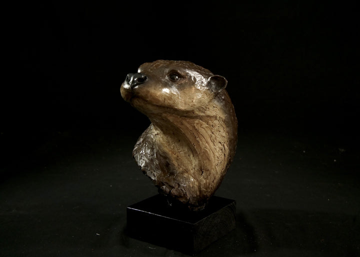 Cold cast stone sculpture of an otter head and neck titled Hindsight by Jamie Lord — finely detailed bust with sleek, sinuous form, warm brown fur tones, dark glassy eyes and alert, turned-back pose. Limited edition of 24 with signed Certificate of Authenticity.