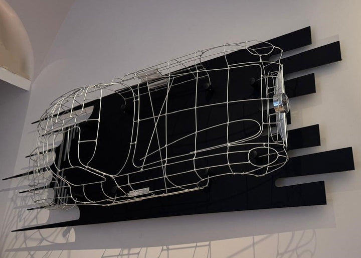 Handcrafted Mercedes-Benz 300 SLR Coupé wire sculpture by Chris Twitchell, inspired by the legendary 1955 Uhlenhaut prototype designed by Friedrich Geiger. Sculpted from precision-formed steel and finished in silver grey DB180, this wall-mounted piece reimagines one of the rarest and most valuable cars ever built — a celebration of German engineering excellence, aerodynamic form, and timeless automotive design.