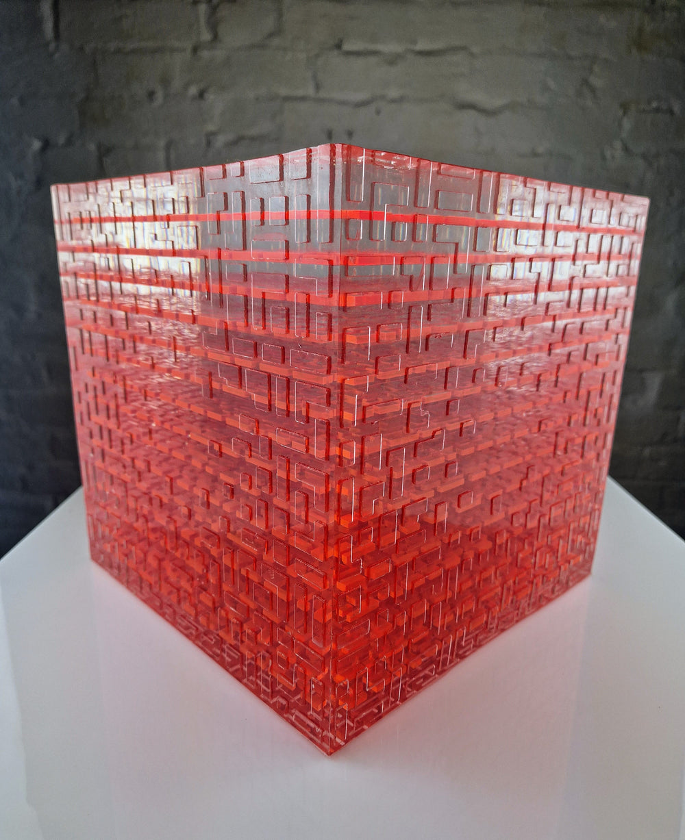 A one-off sculptural cube by Richard Slee, constructed from neon red acrylic and clear resin. The work features a dense, layered grid pattern that plays with light, depth, and shadow—creating a luminous, architectural object with a strong geometric presence. The cube glows from within, drawing the viewer into its intricate interior.