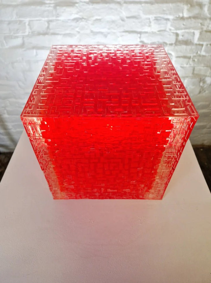 A one-off sculptural cube by Richard Slee, constructed from neon red acrylic and clear resin. The work features a dense, layered grid pattern that plays with light, depth, and shadow—creating a luminous, architectural object with a strong geometric presence. The cube glows from within, drawing the viewer into its intricate interior.