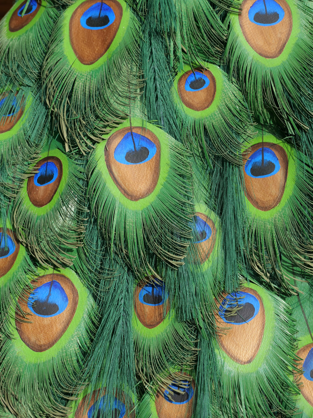 Arrogant Beauty by Jamie Lord – a life-size peacock sculpture meticulously crafted from hand-cut, hand-painted 260gsm pastel paper feathers. The peacock stands proudly atop stacked vintage books, its vivid green and blue plumage cascading nearly to the floor. Designed to symbolise pride, intelligence, and transformation, the sculpture features lifelike detail and rich texture, standing 1.75 metres tall and presented against a luxurious interior backdrop.