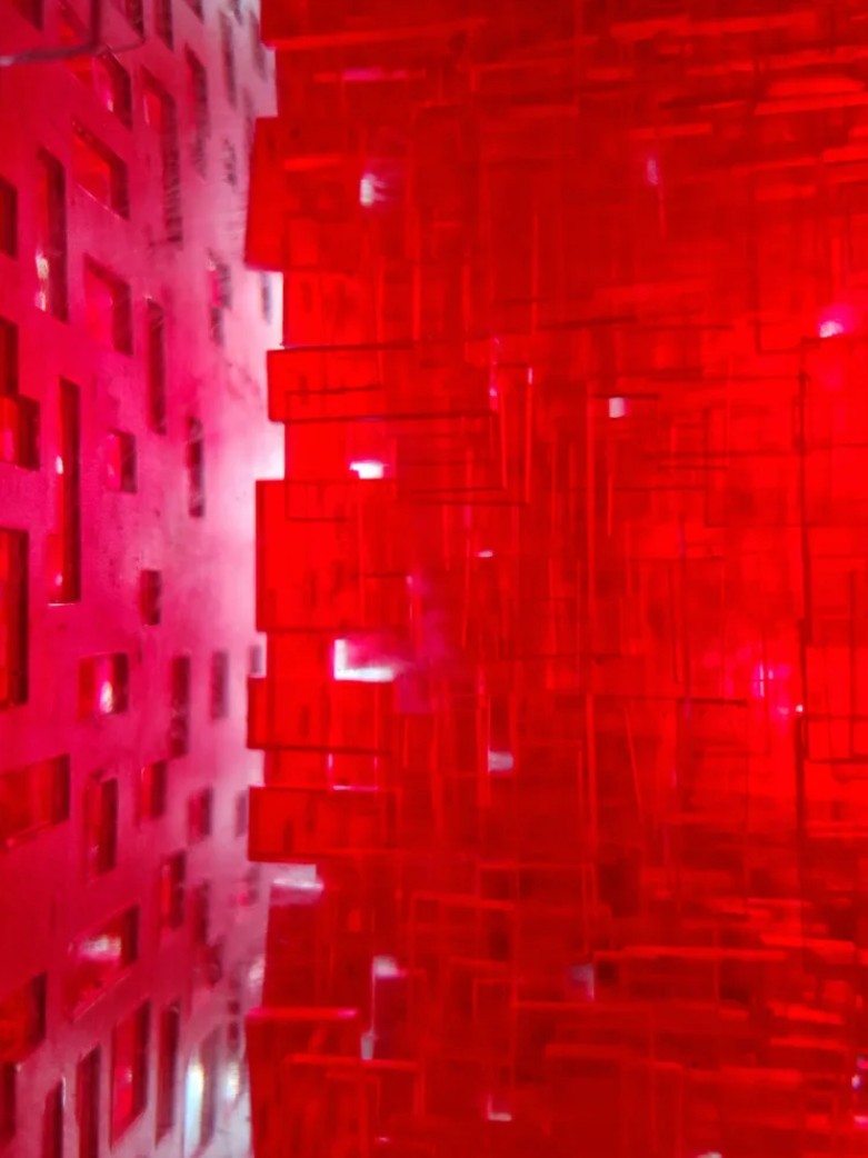 A one-off sculptural cube by Richard Slee, constructed from neon red acrylic and clear resin. The work features a dense, layered grid pattern that plays with light, depth, and shadow—creating a luminous, architectural object with a strong geometric presence. The cube glows from within, drawing the viewer into its intricate interior.