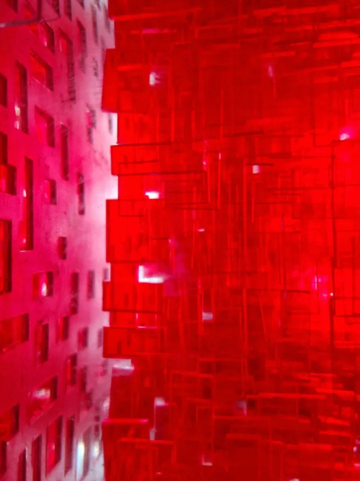A one-off sculptural cube by Richard Slee, constructed from neon red acrylic and clear resin. The work features a dense, layered grid pattern that plays with light, depth, and shadow—creating a luminous, architectural object with a strong geometric presence. The cube glows from within, drawing the viewer into its intricate interior.