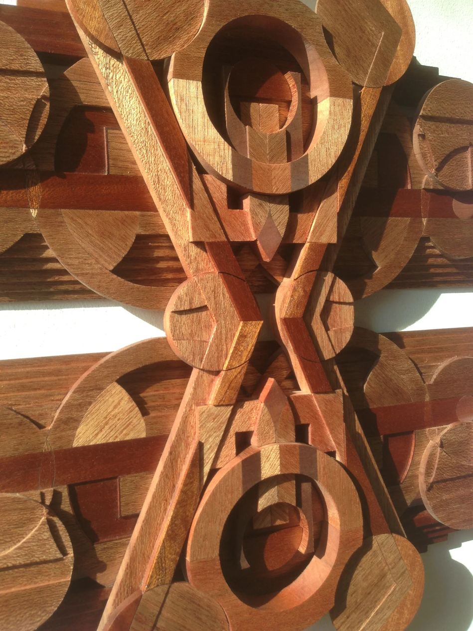 Hand-carved wooden wall sculpture by Richard Slee titled “Solar Differentials,” crafted from Meranti wood in a symmetrical, radial composition. Features geometric layering, concentric circles, and intersecting lines with warm red-brown natural wood tones.