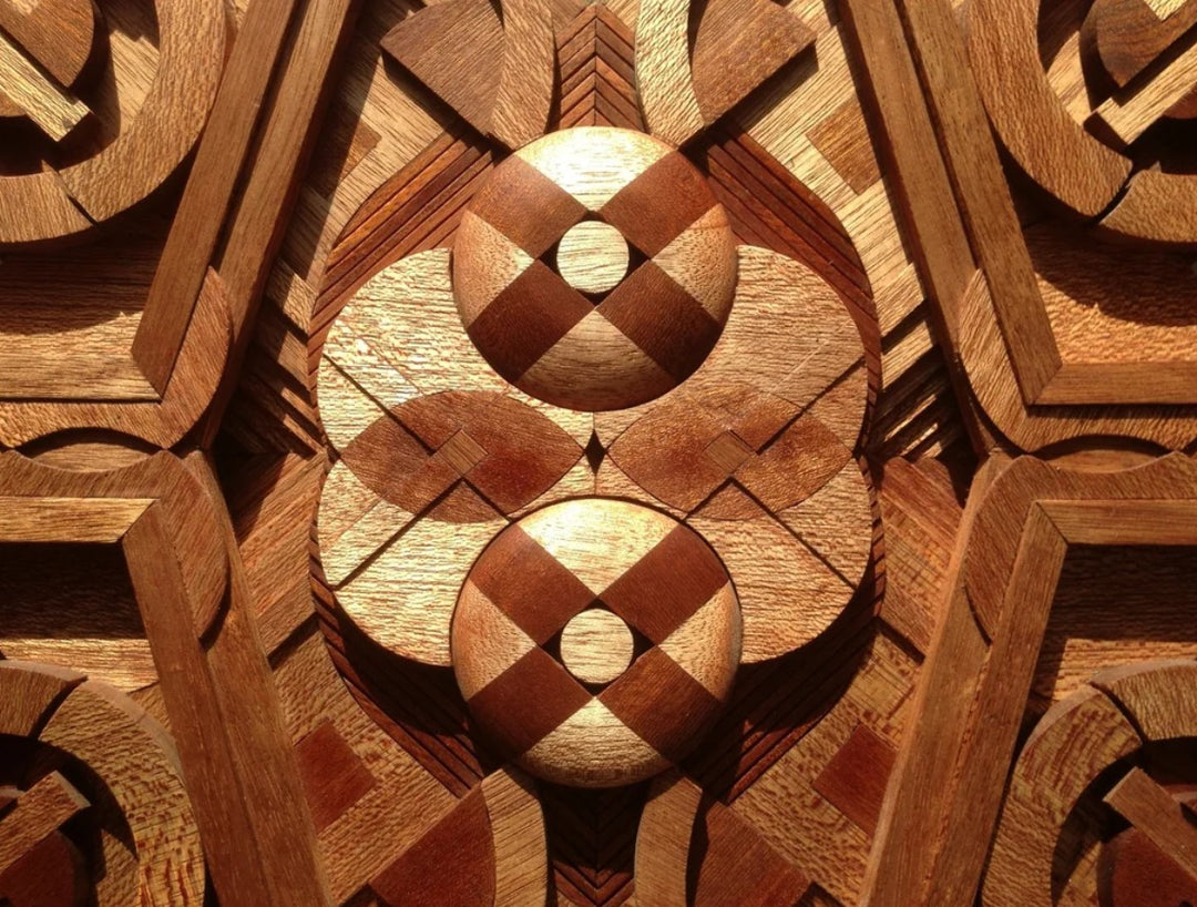 Intricately carved geometric wall sculpture by Richard Slee, made from Meranti wood in layered radial symmetry. The piece features intersecting circles, angles, and sculpted depth, with natural reddish-brown wood tones enhancing its three-dimensional, architectural feel.