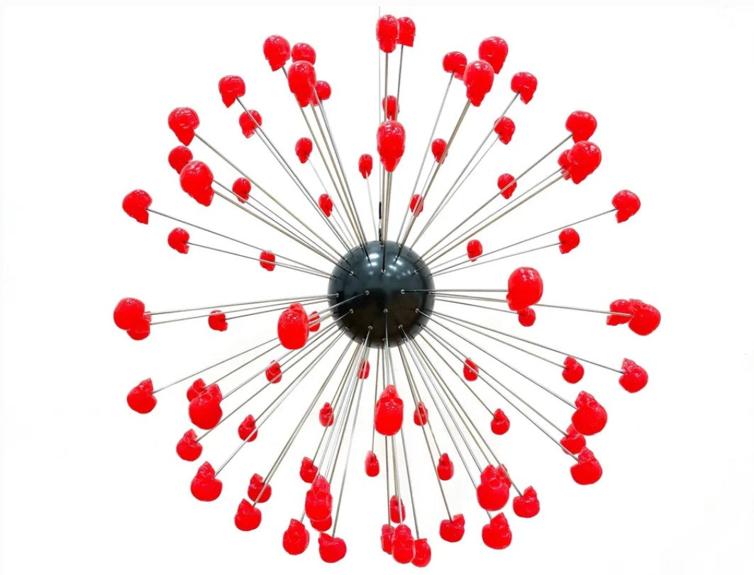 Large spherical hanging sculpture composed of a central black metallic orb with over 70 radiating stainless steel rods, each tipped with a glossy red sculpted skull. The skulls appear to orbit the sphere like a molecular explosion or stylised dandelion, creating a dramatic and surreal visual impact. Materials include stainless steel, polymorph and resin, with vibrant red gloss details and industrial metallic finishes.