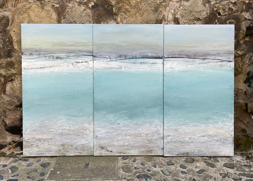 'Across The Bay, St Ives' by Heather McAlpine, an original large-scale triptych seascape painting in acrylic on canvas inspired by the panoramic beauty of St Ives Bay, Cornwall. Three connected panels depict pale turquoise waters, silvery shoreline and soft grey skies, capturing the shifting light, tide and tranquillity of the Cornish coast in an immersive contemporary composition.