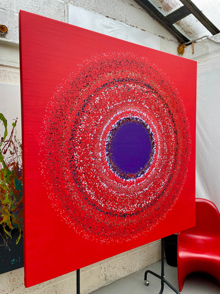 Large abstract painting “Ellipsis” by Swarez — bold square composition with a deep violet central circle surrounded by concentric rings of paint droplets and splashes on a vivid matte red background. Energetic, dynamic halo effect created by spin technique.