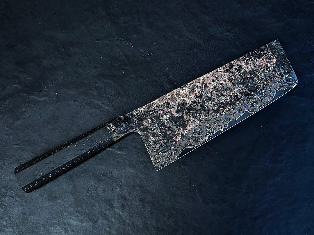 One-of-a-kind Cu-Ni-Mascus Nakiri knife by Leszek Sikon, showcasing 8120 layers of Damascus forged from Spicy White steel, O1 tool steel, copper, nickel, and brass. The blade features a rich, geological pattern with molten textures and wave-like lines, hand-forged over 100 hours with an S-profile for food release and finished with a custom jeans micarta handle embedded with copper and steel mesh.