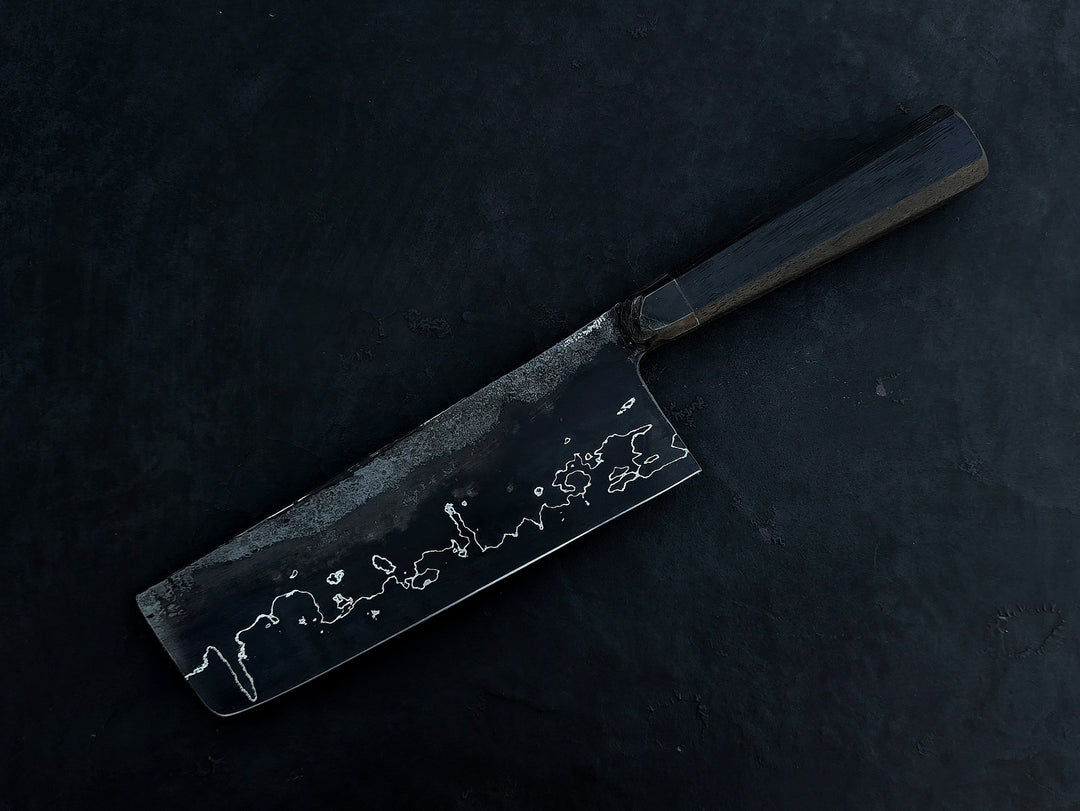 Leszek Sikon San Mai Graphite Nakiri hand-forged kitchen knife featuring a dark laminated carbon steel blade with visible hamon line and bog oak handle.
