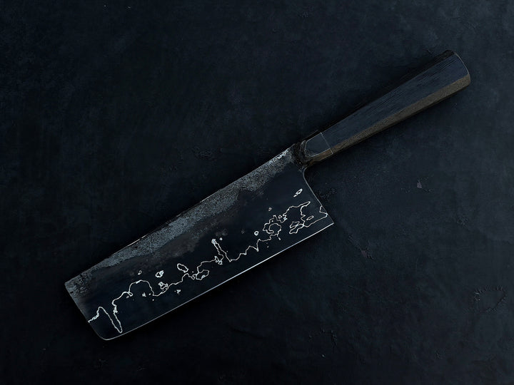 Leszek Sikon San Mai Graphite Nakiri hand-forged kitchen knife featuring a dark laminated carbon steel blade with visible hamon line and bog oak handle.