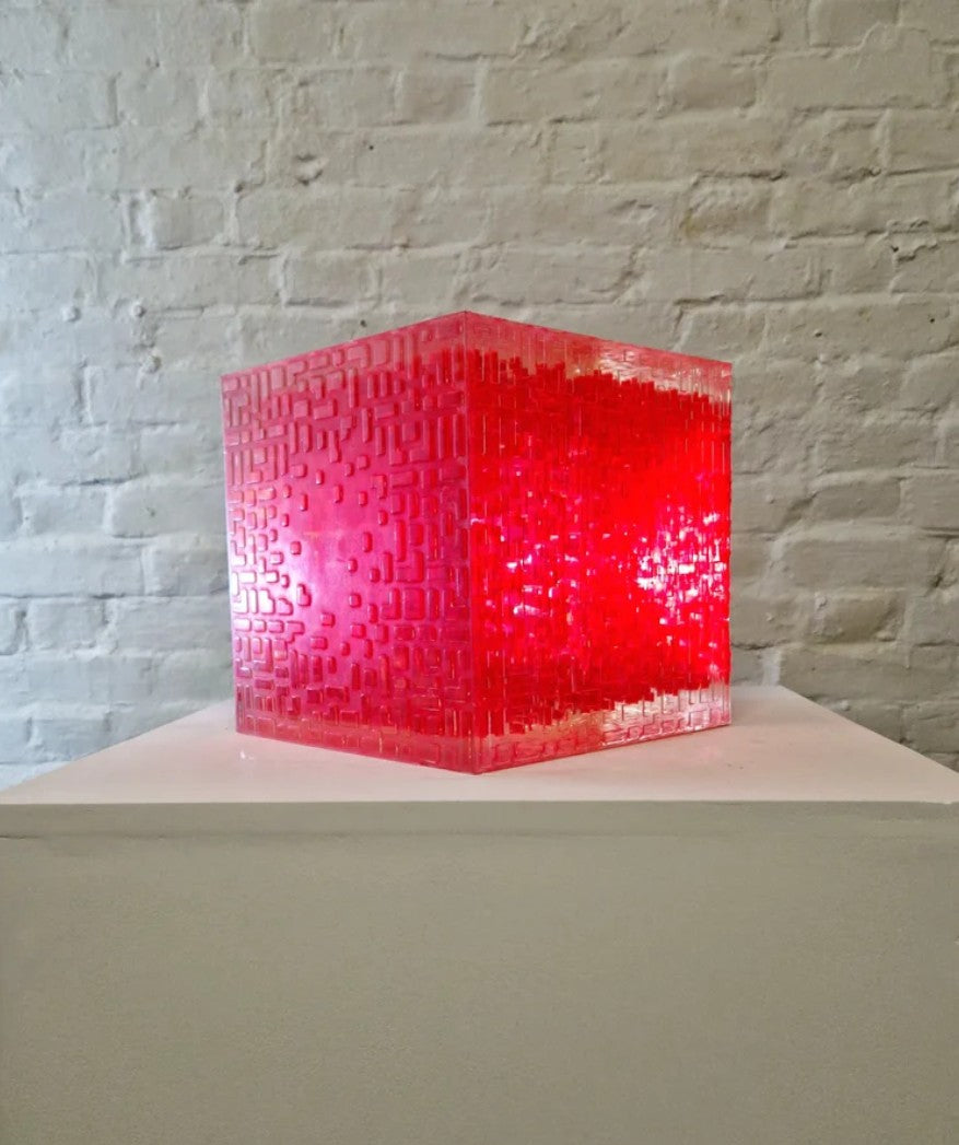 A one-off sculptural cube by Richard Slee, constructed from neon red acrylic and clear resin. The work features a dense, layered grid pattern that plays with light, depth, and shadow—creating a luminous, architectural object with a strong geometric presence. The cube glows from within, drawing the viewer into its intricate interior.