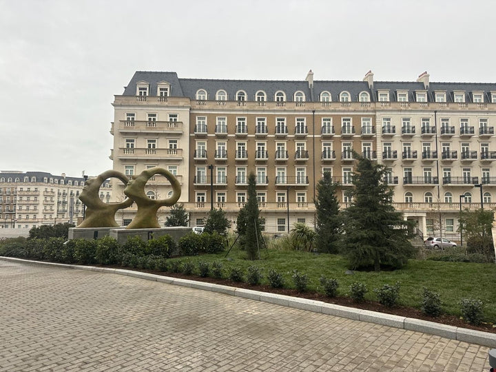 Simon Gudgeon bronze sculpture Search for Enlightenment featuring monumental interlocking abstract human forms with circular openings displayed within a landscaped outdoor setting.