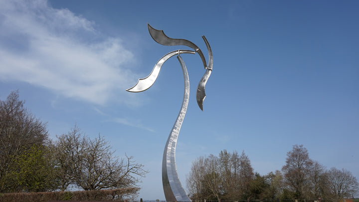 Abstract stainless steel kinetic sculpture with wind-responsive curved elements designed to shift and flow with natural movement