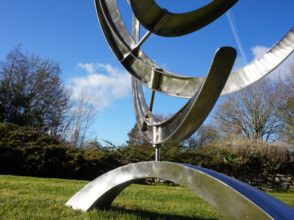 Freestanding kinetic sculpture with layered, flame-like curves designed to rotate or shift gently with the wind