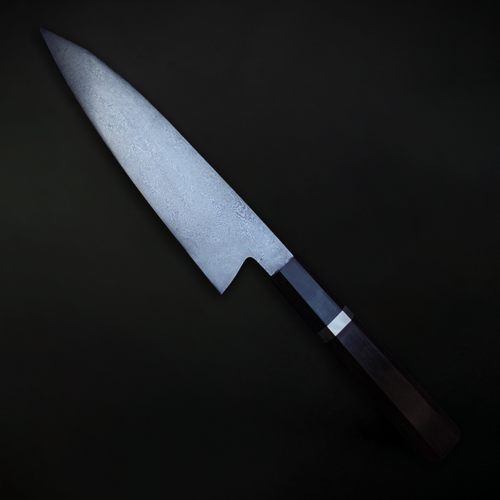 210mm high-layer Damascus chef’s knife, hand-forged from 15N20 and 80Crv2 carbon steels, featuring a deeply etched, topographic blade surface and a sculpted black wood handle with matching ferrule.