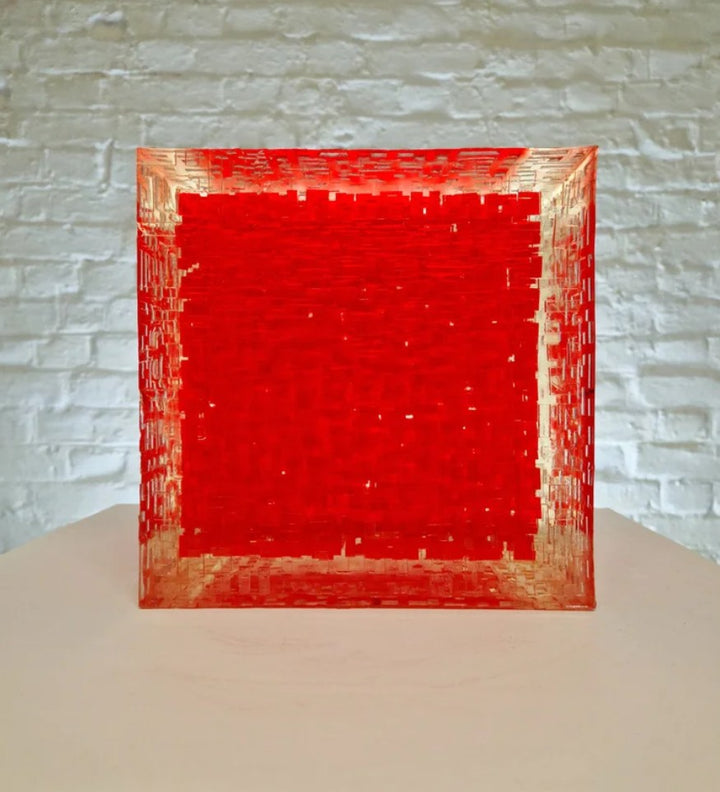 A one-off sculptural cube by Richard Slee, constructed from neon red acrylic and clear resin. The work features a dense, layered grid pattern that plays with light, depth, and shadow—creating a luminous, architectural object with a strong geometric presence. The cube glows from within, drawing the viewer into its intricate interior.