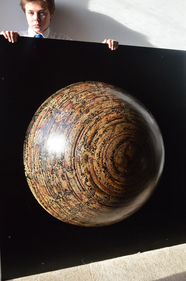Textured hemispherical sculpture by Richard Slee titled “Nebula Core.” Made from hundreds of upright bamboo skewers embedded in black resin, the surface is meticulously hand coloured with pencil in swirling, planetary patterns. The final effect resembles a cosmic vortex or galactic core, rendered in warm earthy tones with rich texture and depth.