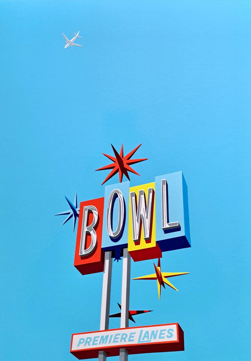 A hand-cut vinyl artwork of a retro American bowling alley sign reading "BOWL" and "Premiere Lanes" beneath it. The composition features bold red, blue, and yellow lettering set against a vivid sky blue background, with atomic-era starbursts and a jet flying overhead. The piece captures mid-century Americana with clean lines and pop-art energy.
