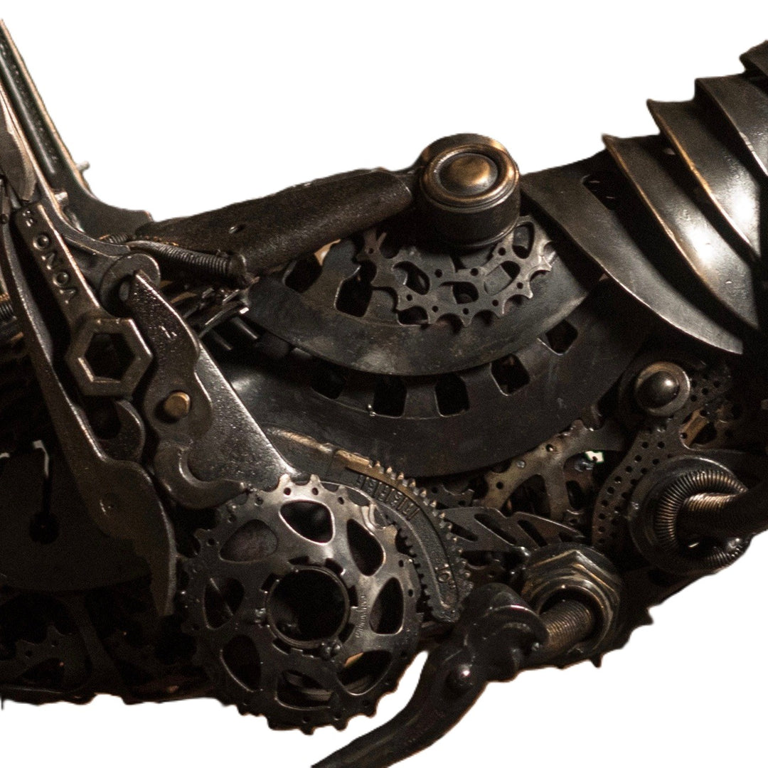 Mechanical grasshopper sculpture crafted from reclaimed metal and gears, displayed on a rustic workbench.