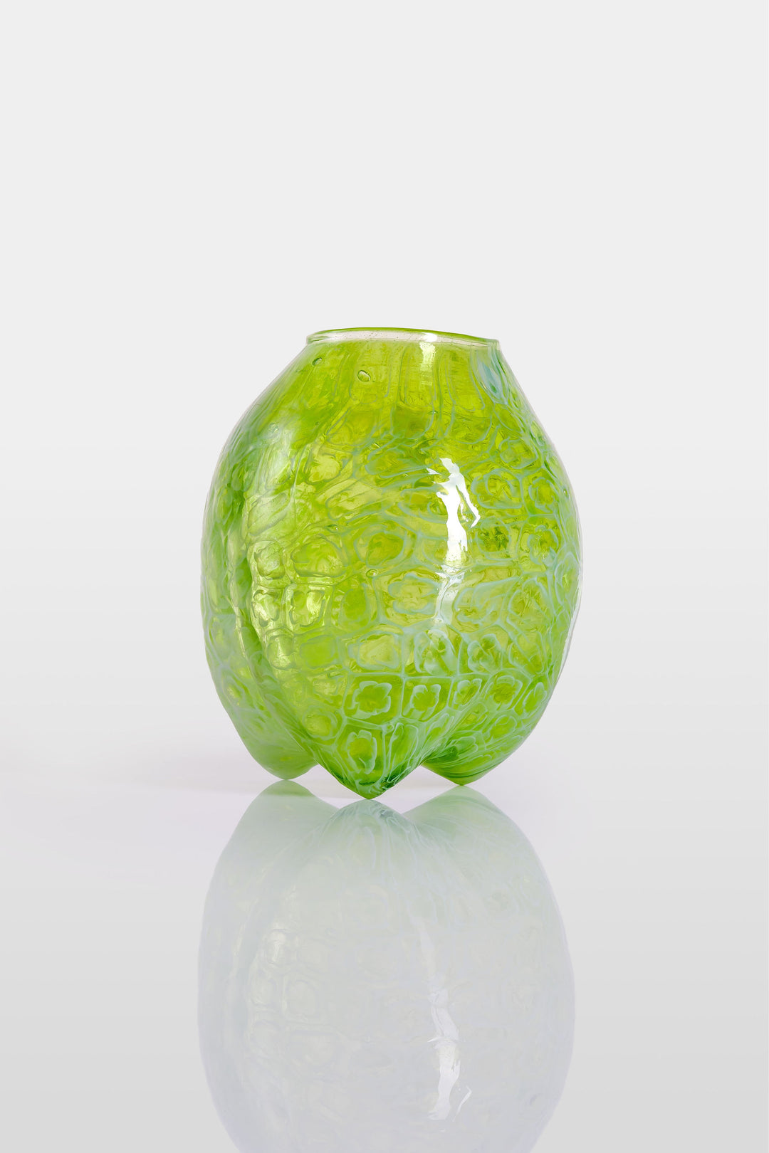 Blown green glass vessel with embossed floral-like texture and a softly bulbous form, featuring a subtly dimpled base and translucent finish.