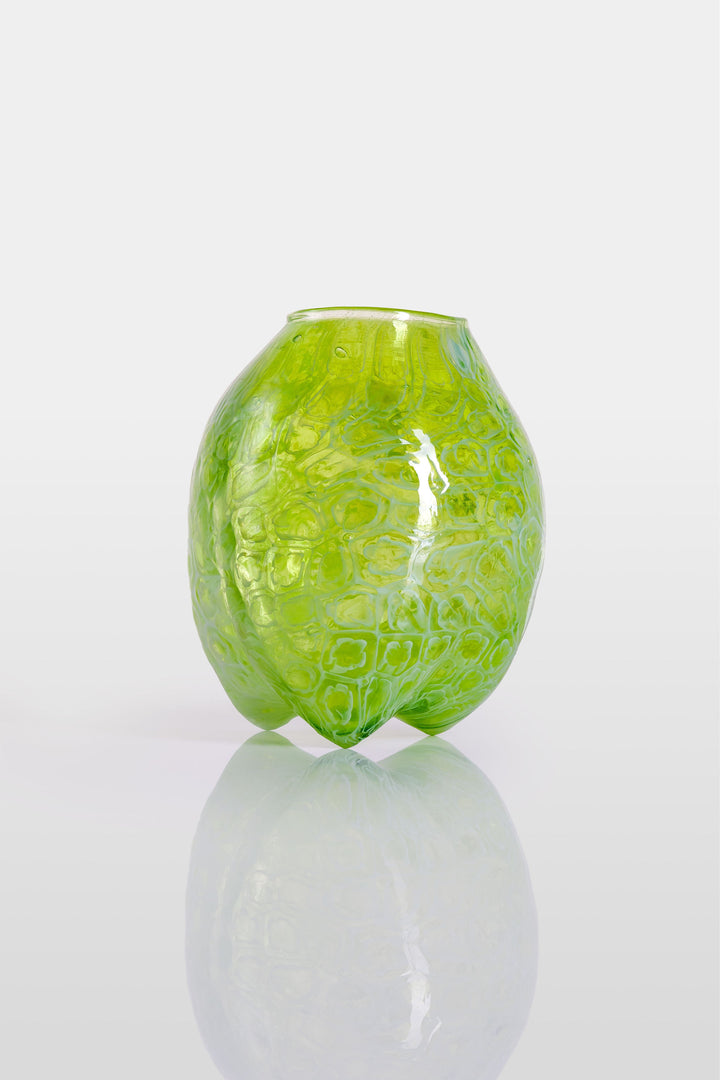 Blown green glass vessel with embossed floral-like texture and a softly bulbous form, featuring a subtly dimpled base and translucent finish.
