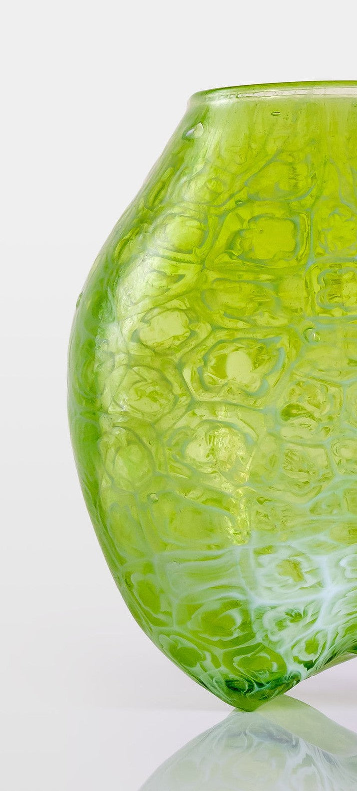 Blown green glass vessel with embossed floral-like texture and a softly bulbous form, featuring a subtly dimpled base and translucent finish.