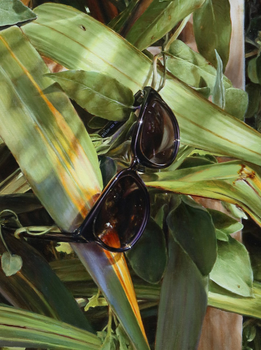 Arina Gordienko hyperrealist oil painting After You, depicting a wooden frame entwined with dense green foliage, where everyday objects—a spiral light bulb, iPhone charger cable, and dark sunglasses—hang among the leaves. Painted during lockdown, the work reflects themes of absence, memory, and what remains after us.
