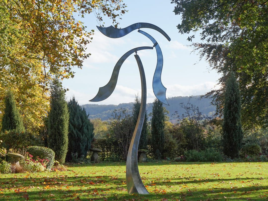 Abstract stainless steel kinetic sculpture with wind-responsive curved elements designed to shift and flow with natural movement