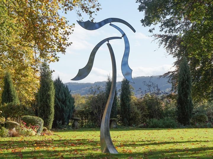 Abstract stainless steel kinetic sculpture with wind-responsive curved elements designed to shift and flow with natural movement