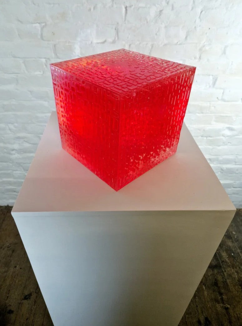 A one-off sculptural cube by Richard Slee, constructed from neon red acrylic and clear resin. The work features a dense, layered grid pattern that plays with light, depth, and shadow—creating a luminous, architectural object with a strong geometric presence. The cube glows from within, drawing the viewer into its intricate interior.