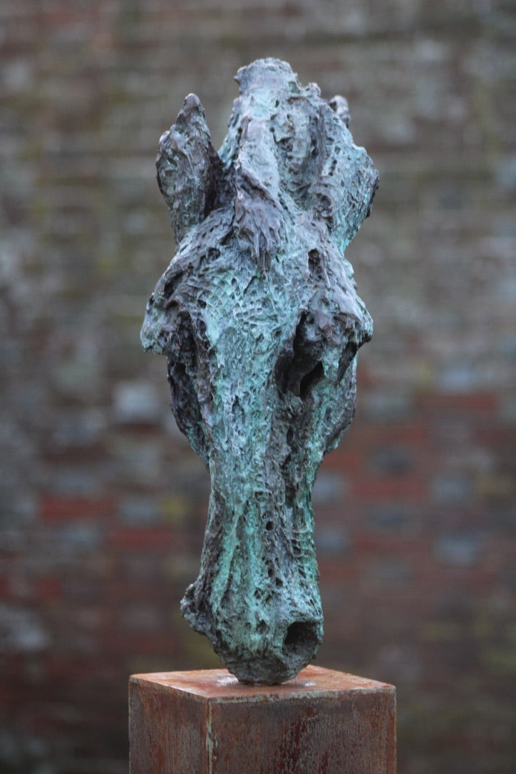 Abstract bronze sculpture of a horse’s head, mounted on a tall corten steel plinth, displayed in various garden and outdoor settings. The textured verdigris patina highlights the expressive contours and emotional form of the equine subject.