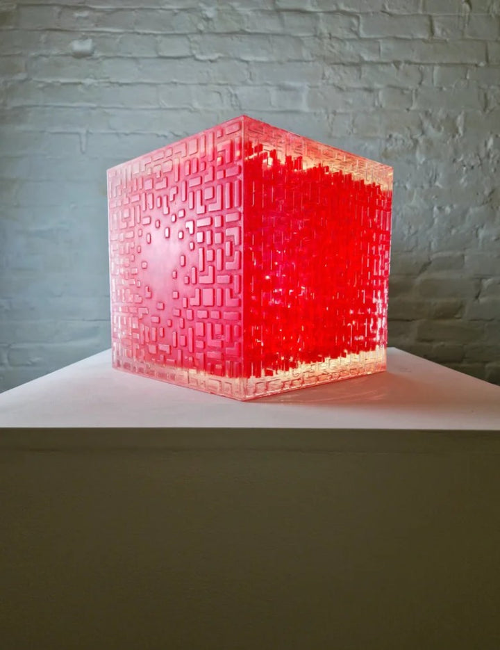 A one-off sculptural cube by Richard Slee, constructed from neon red acrylic and clear resin. The work features a dense, layered grid pattern that plays with light, depth, and shadow—creating a luminous, architectural object with a strong geometric presence. The cube glows from within, drawing the viewer into its intricate interior.