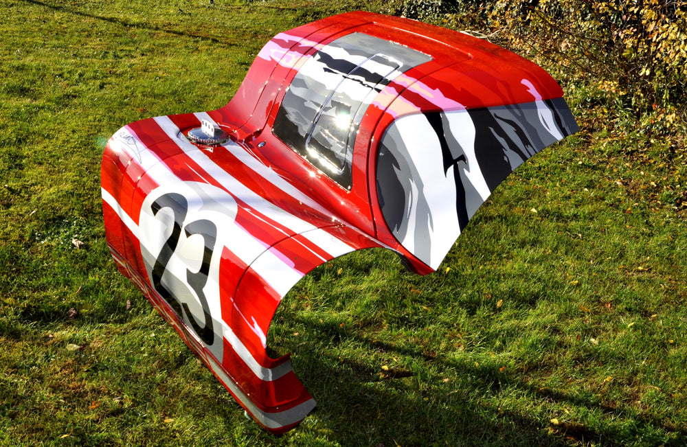 Custom-painted red and white racing car body panel featuring number 23 and abstract black and grey graphics.
