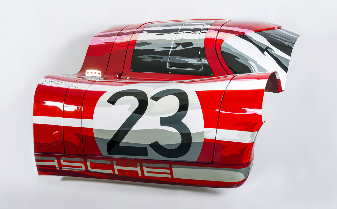 Custom-painted red and white racing car body panel featuring number 23 and abstract black and grey graphics.

